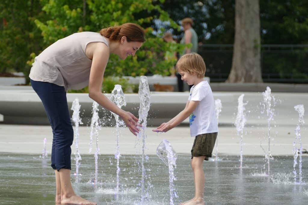 mom playing in fountain with son